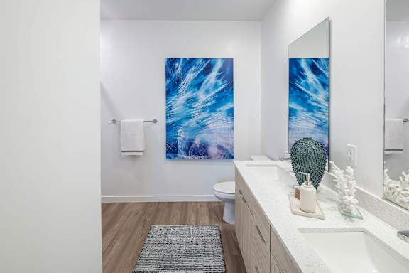 A bathroom with a large painting of a blue wave on the wall.