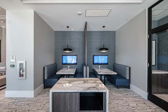 A modern waiting area with two TVs on the wall at Altis Santa Barbara, Florida