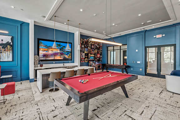 a game room with a red pool table and a television at Altis Twin Lakes Apartments, Kissimmee, 34744