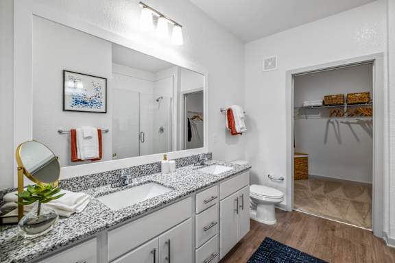 A bathroom with a granite countertop and white cabinets.