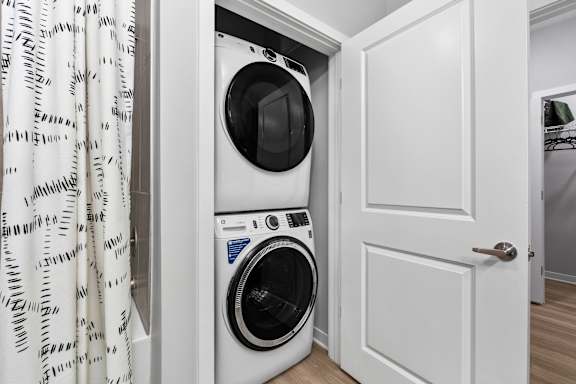 A white washing machine is in a small white closet.