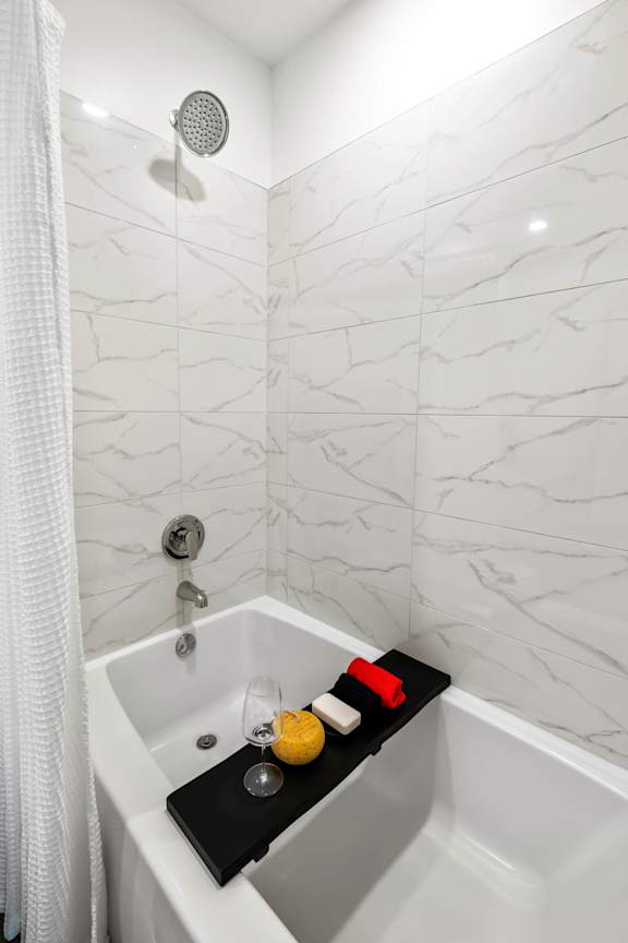 A white bathtub with a black mat and a lemon on it.