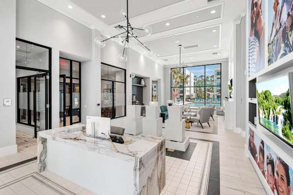 A modern office lobby with a reception desk and a large screen on the wall.