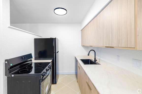A kitchen with a black stove top oven and black refrigerator.