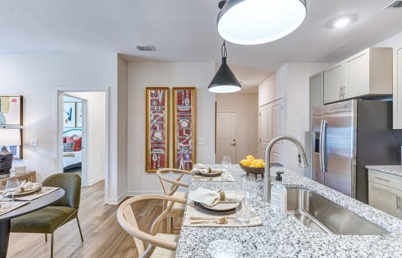 a kitchen and living room with a granite counter top and a stainless steel refrigerator