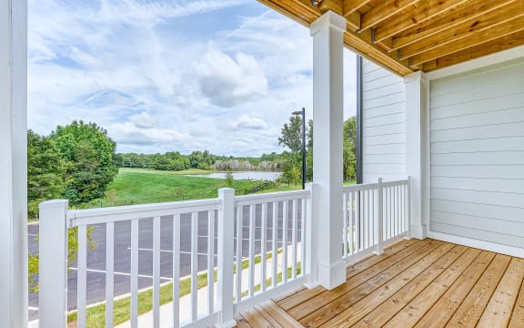 a porch with a view of a field and a lake