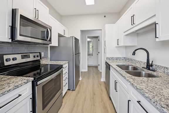 A kitchen with white cabinets and granite countertops.