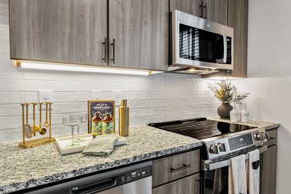 A kitchen with granite countertops and a microwave above the stove.