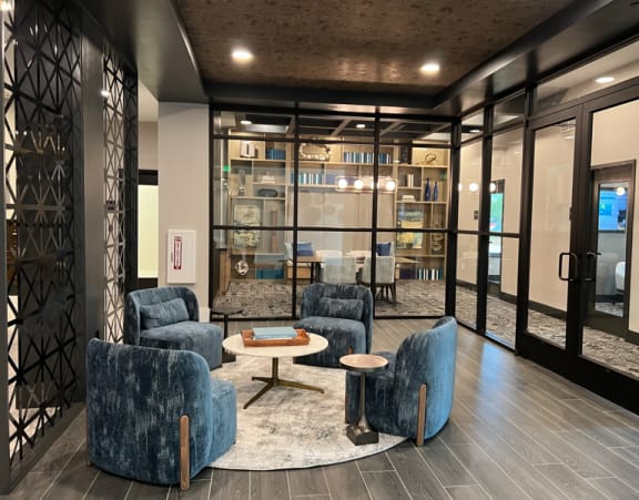 a lounge area with blue chairs and tables and glass doors