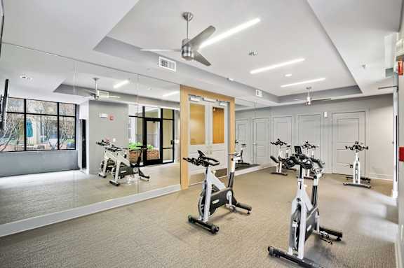 A gym with a row of stationary bikes and a mirrored wall.