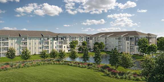 A large building complex with a pond in front.