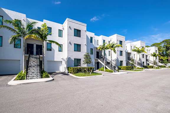 A row of white houses with palm trees in front.