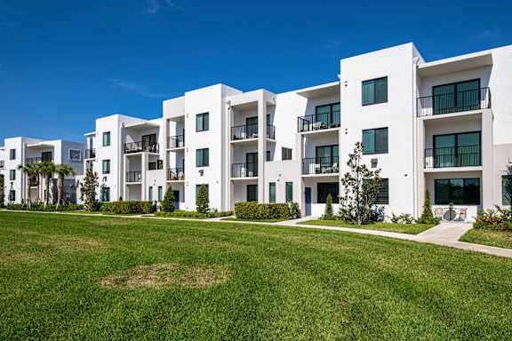 A row of white apartment buildings with green lawns in front.