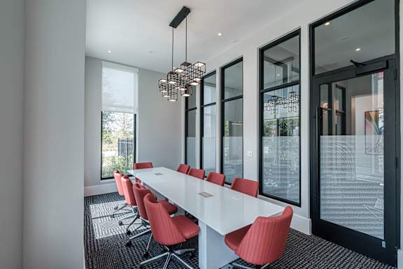 a long table with red chairs in a room with large windows at Altis Twin Lakes Apartments, Kissimmee, Florida