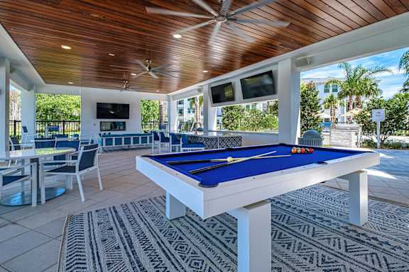 a pool table in a covered patio with tables and chairs at Altis Twin Lakes Apartments, Florida