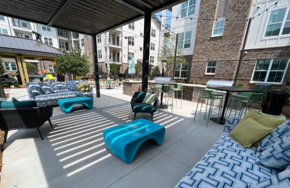 a patio with blue benches and chairs and tables in front of an apartment building