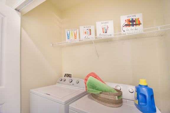 A laundry room with a washer and dryer and ironing board.