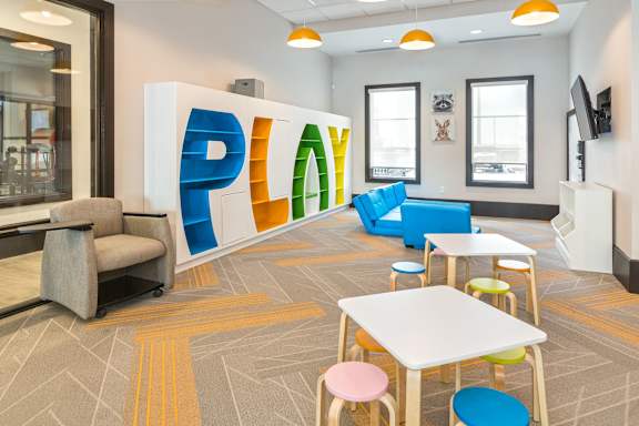 A room with a white table and chairs and a large PLAY sign.