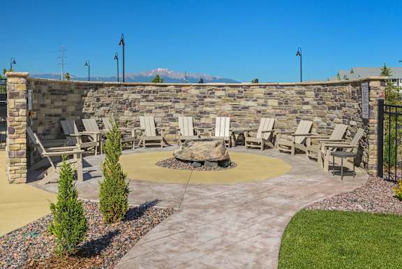 A patio with a fire pit and chairs.