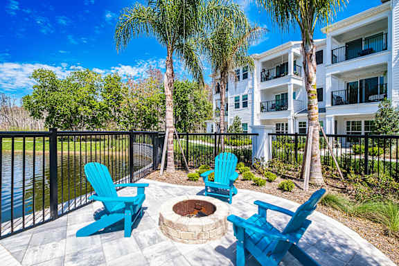 A patio with blue chairs and a fire pit in front of a building
