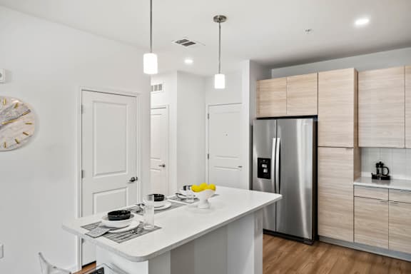 A modern kitchen with a white table and a stainless steel refrigerator.