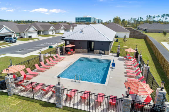 an aerial view of a swimming pool with red chairs and umbrellas