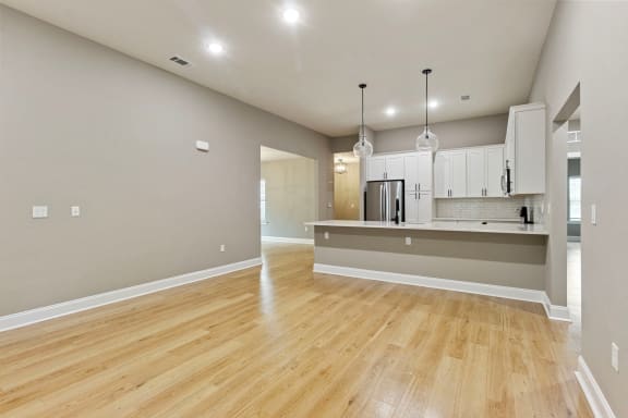 an empty living room and kitchen with a hard wood floor