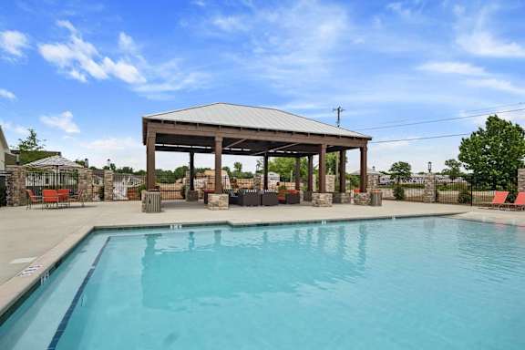 A pool with a pavilion in the background.