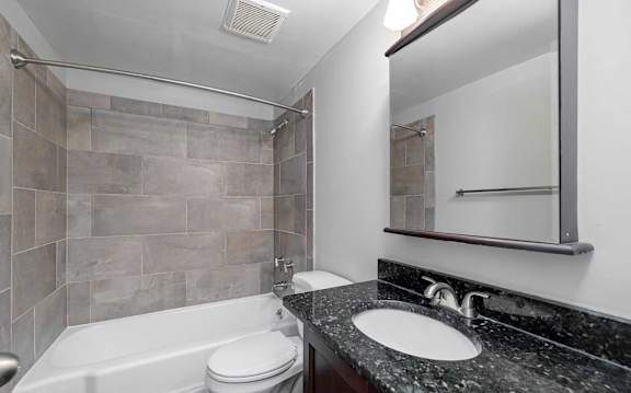 A bathroom with a tub, sink and mirror.
