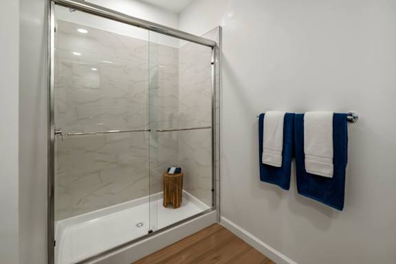 A white bathroom with a glass shower door and a white tub.