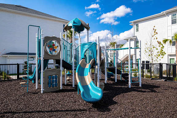 A playground with a blue slide and a brown ground
