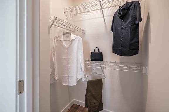 a walk in closet with a shirt and jacket hanging on a rack at Altis Twin Lakes Apartments, Kissimmee, FL