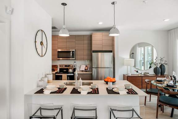 A modern kitchen with a large island and chairs.