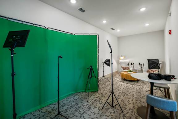 A photo studio with a green screen, lighting equipment, and a table with a bowl of snacks.at Altis Grand Lake Willis, Orlando, FL 32821