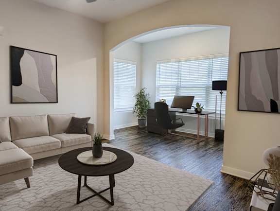 A living room with a white couch, a black chair, and a small table with a plant on it.