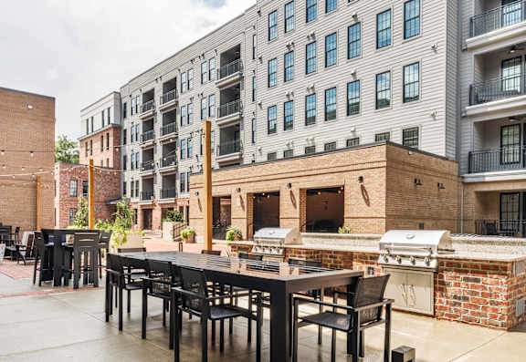 A patio with a table and chairs is surrounded by brick buildings.