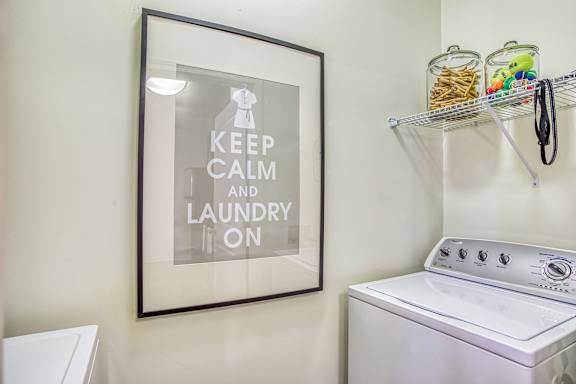 A laundry room with a washing machine and a sign that says "Keep Calm and Laundry On".