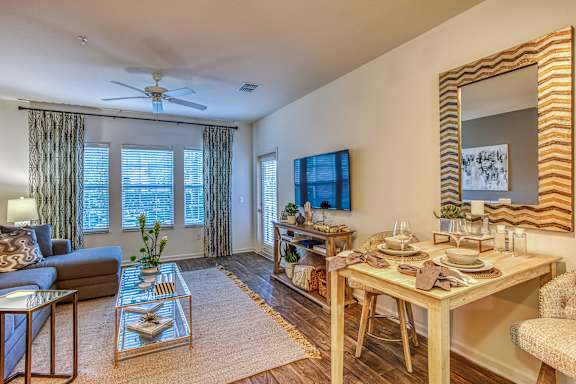 A well-lit living room with a dining table set for two.