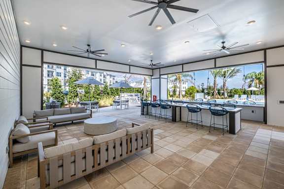 A patio with a table and chairs is surrounded by a wall and has a ceiling fan.at Altis Grand Lake Willis, Orlando, 32821