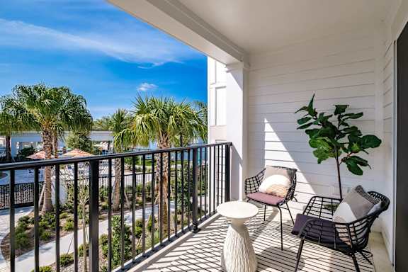 a balcony with two chairs and a table and a view of the water at Altis Twin Lakes Apartments, Kissimmee, FL 34744