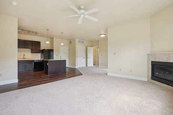 A spacious living room with a fireplace and a ceiling fan.