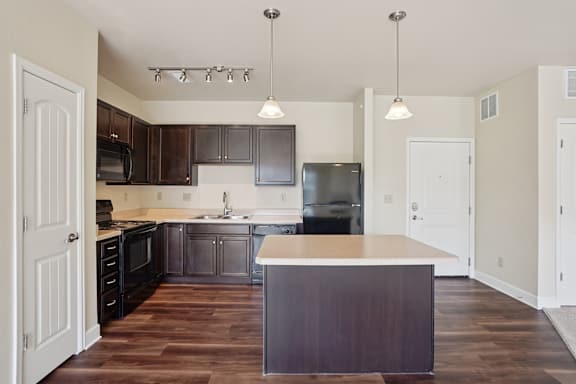 A kitchen with dark wood cabinets and a white island.