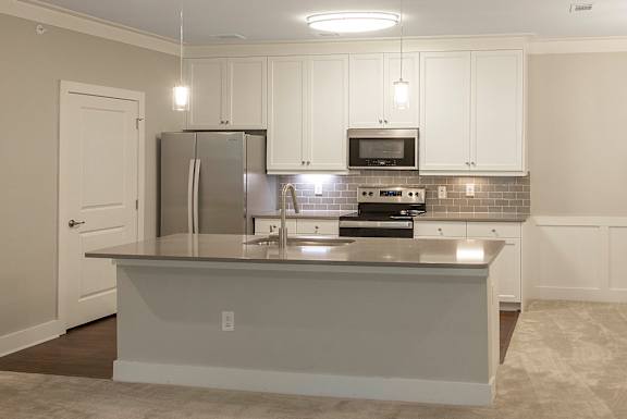 A kitchen with white cabinets and a stainless steel refrigerator.