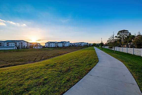 A pathway leads through a grassy area with a sunset in the background.at Altis Grand Lake Willis, Orlando Florida
