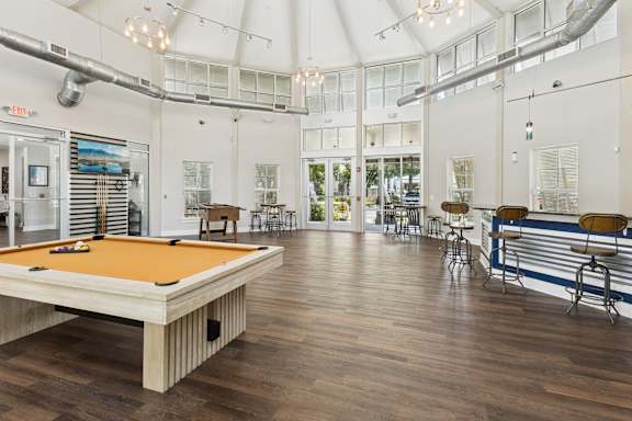 A pool table is in the middle of a room with a bar and a pool table.