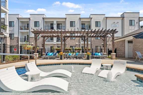 A pool area with a wooden pergola and lounge chairs.