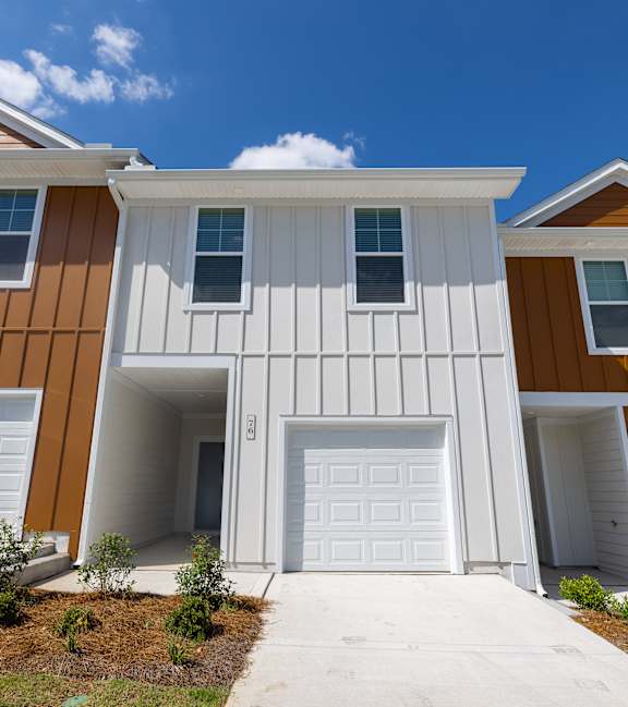 A modern house with a white garage door and brown sidings.