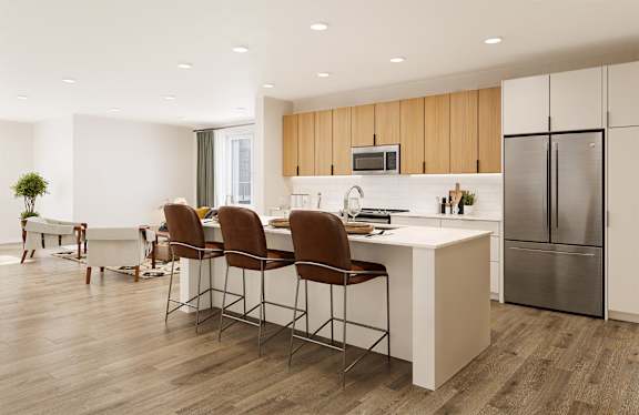 A modern kitchen with a white island and brown chairs.