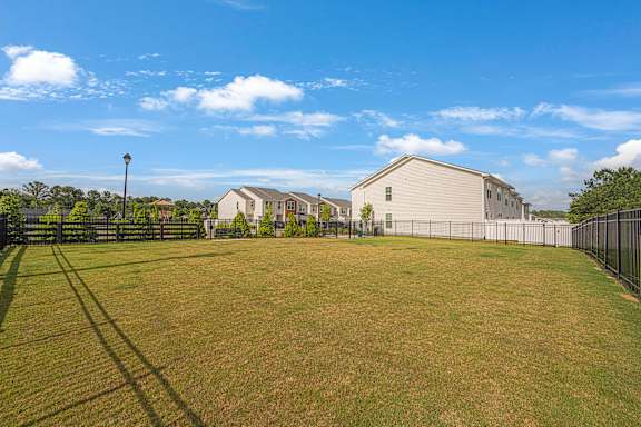 A grassy field with a fence and a building in the background.