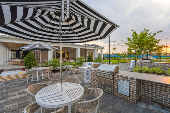 a patio with a grill and tables with umbrellas